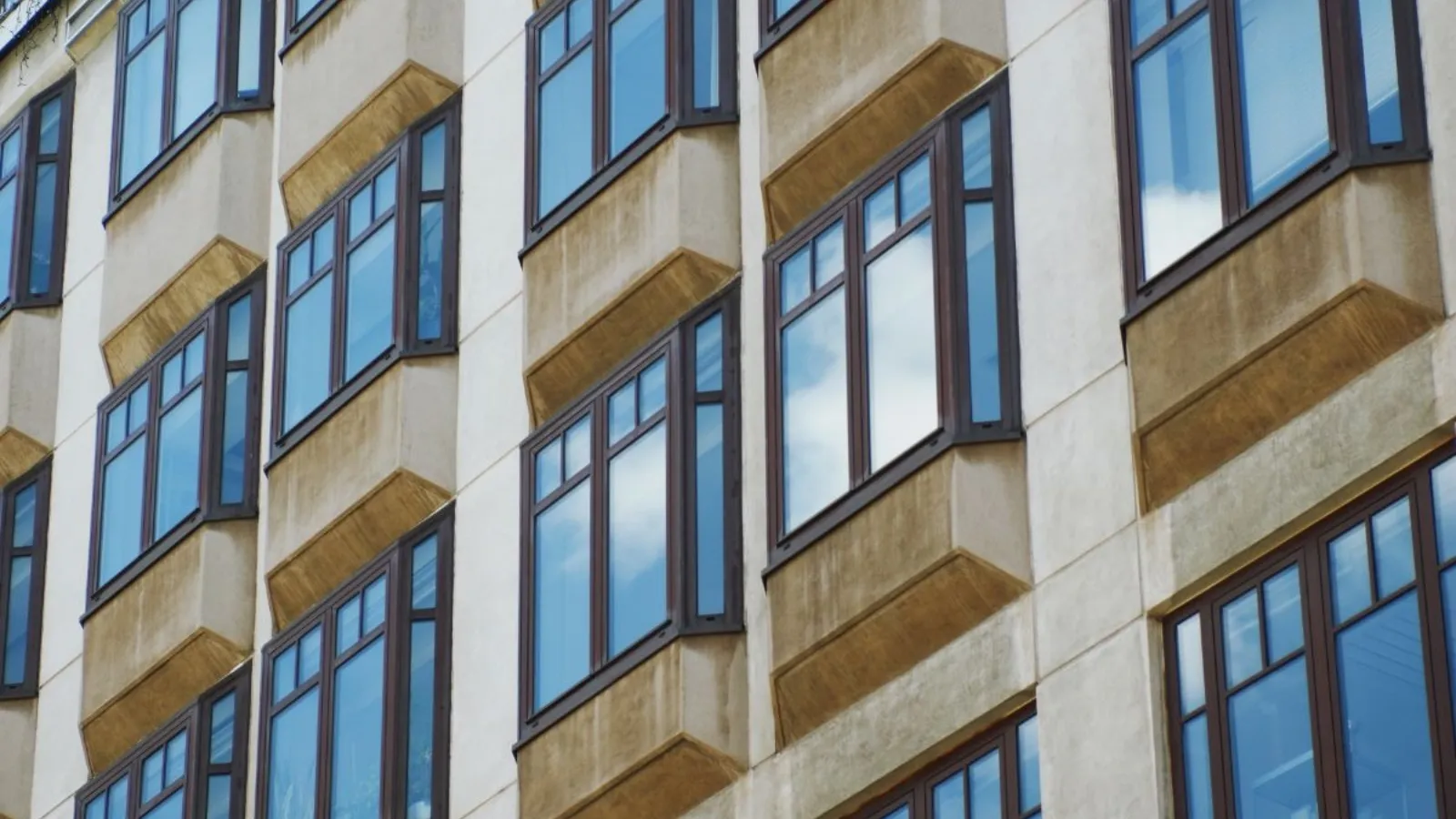 A modern office facade seen from below, its bay windows repeating in even rows across the frame.