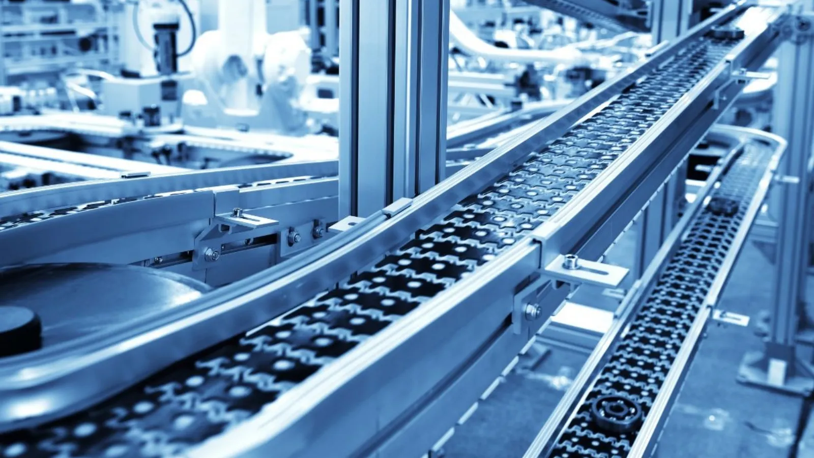 An empty conveyor belt running away from the camera through a quiet packing line.