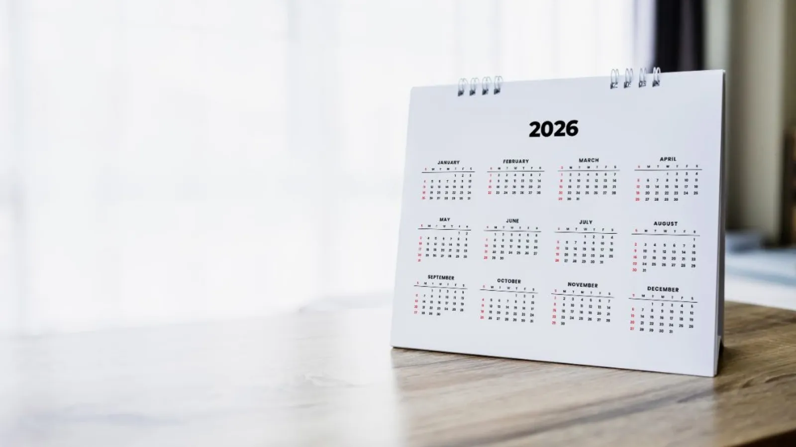 A wall-mounted calendar with several months visible, photographed at an angle in low light.